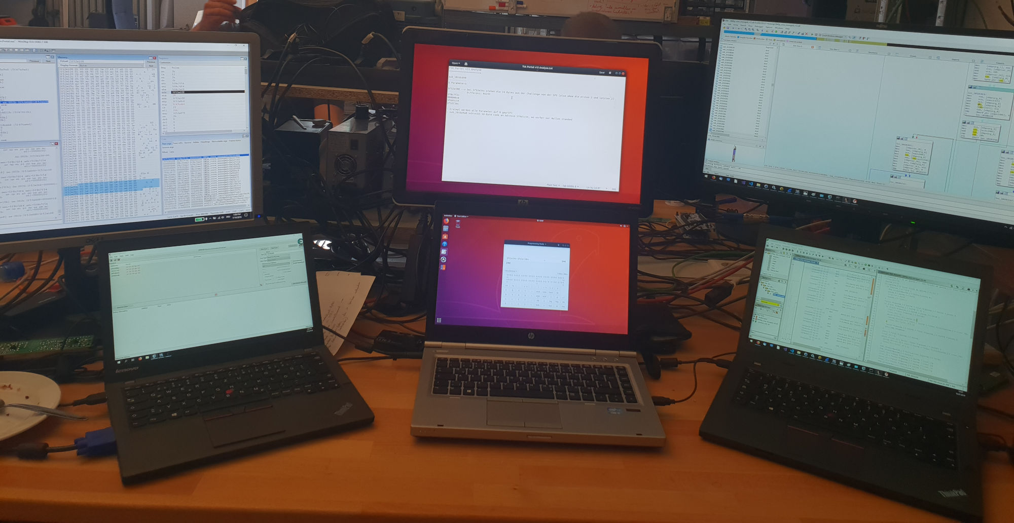 3 laptops with 2 screens each, running WinDbg, Cheat Engine, a text editor, a calculator, IDA and Ghidra -- A photo from the early days of ENLYZE